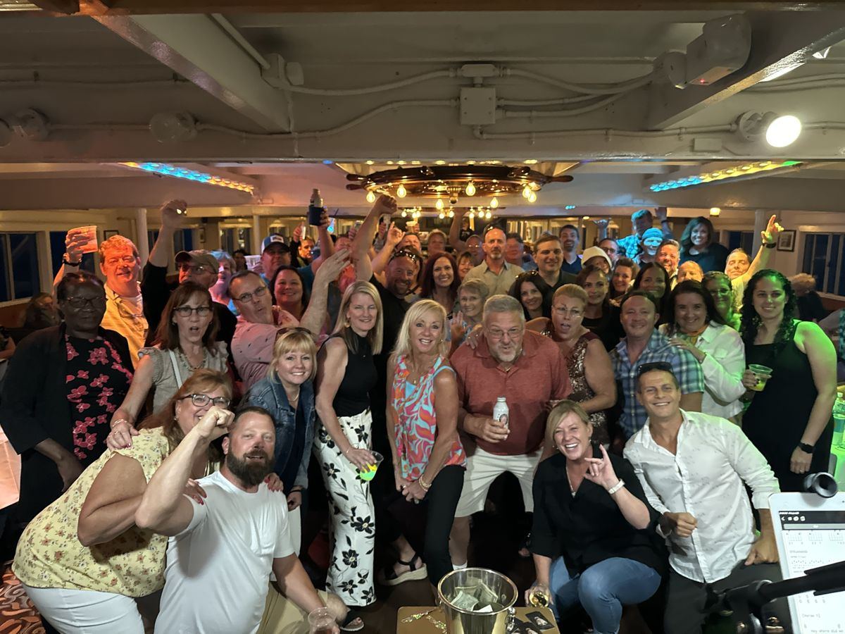 A big crowd cheering at a party on a boat